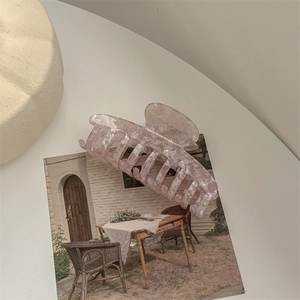 Detail of large acetate hair claw clip with pink marble texture on decorative magazine