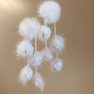 Detailed view of white faux fur pompom earrings with fabric roses and crystal beads