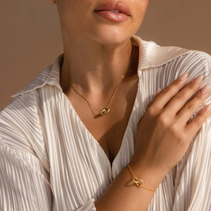Detailed close-up of gold interlocking double rings on necklace and bracelet set worn by a model