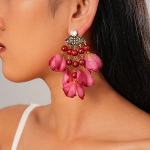 Close-up of model wearing fan-shaped fabric petal earrings with rhinestones and red beads