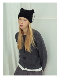 Detail of hand-knitted cat ear beanie with bow and dark grey textured cardigan