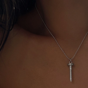 Close-up of a silver screw pendant necklace with beaded chain on a model neck