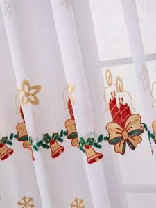Detailed close-up of white Christmas tulle curtain with red candle and bell embroidery