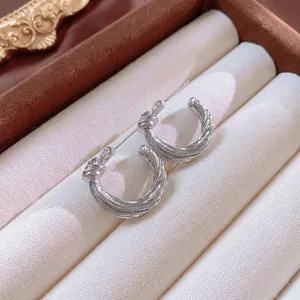 Elegant twisted silver hoop earrings with a knot design on a velvet jewelry tray