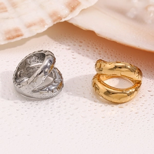 Detail of gold and silver lip-shaped rings with liquid metal texture on white shell surface