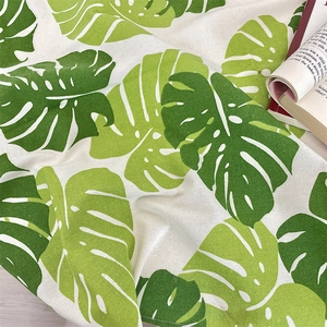 Macro detail of cotton linen tablecloth with vibrant green monstera leaf patterns