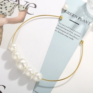 Detailed top view of a gold-tone choker featuring mixed white pearls on a fashion magazine