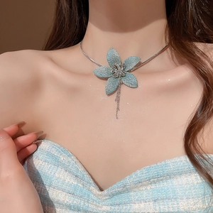 Detailed view of a blue fabric flower pendant necklace with elegant metal tassels