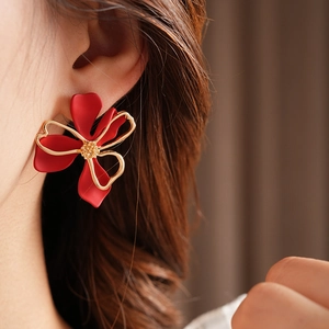 Close-up of a French vintage red matte flower earring with golden accents on a model