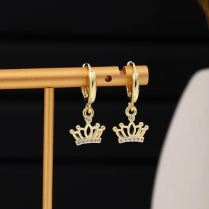 Detail of golden crown earrings with white zircon accents on a professional jewelry display