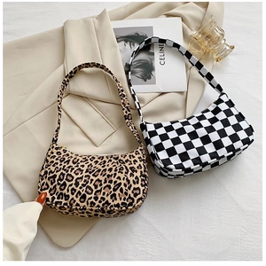 Flat lay of leopard print and checkerboard hobo bags on a beige blazer background