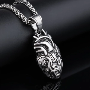Macro d'un pendentif coeur anatomique argenté montrant les détails et veines du métal