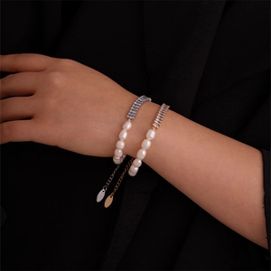 Close-up of pearl and zircon bracelets on wrist against a black background