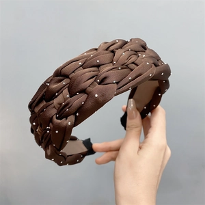Close-up of brown braided satin headband with sparkling rhinestones and textured fabric detail