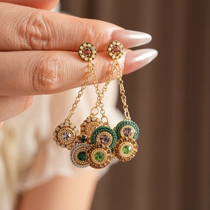 Gros plan de boucles d'oreilles vintage à pompons avec gemmes colorées et dorures