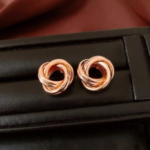 Vue macro de boucles d'oreilles nœud d'amour or rose sur un présentoir en cuir noir
