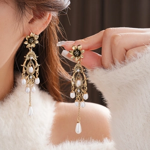 Close-up of vintage sunflower earrings with white pearl tassels and golden finish