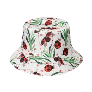 White bucket hat with colorful ladybug prints and green leaf patterns on canvas fabric
