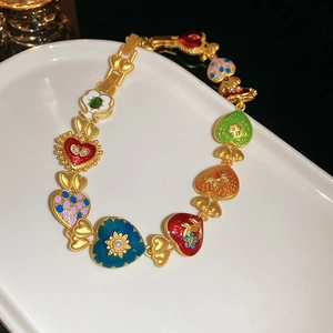 Detailed macro view of vintage gold chain bracelet with colorful enamel floral hearts