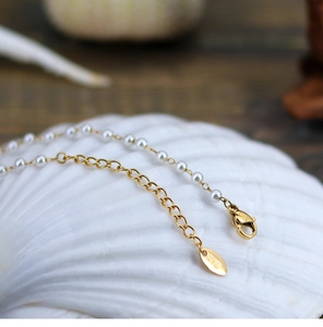 Macro detail of French pearl necklace with K18 gold clasp and seashell background