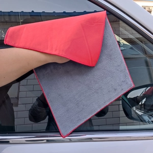 Close-up of red and grey microfiber cloth wiping a car window for effective cleaning