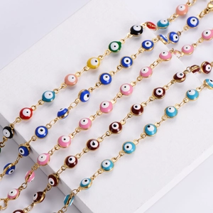 Colorful Evil Eye charm bracelets with gold chains displayed on white geometric steps