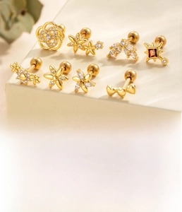 Detail of 8-piece gold-plated titanium steel piercing studs set with heart and flower shapes