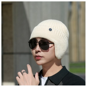 Close-up of thick knit beige winter earflap hat with decorative silver metal button detail