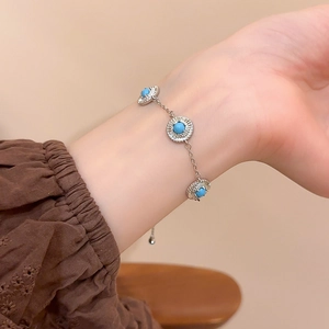 Détail d'un bracelet chaîne en argent avec pierres bleu turquoise et diamants pavés