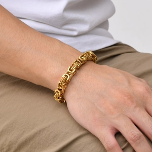 Close-up of a thick gold Byzantine chain bracelet on a man wrist with retro styling
