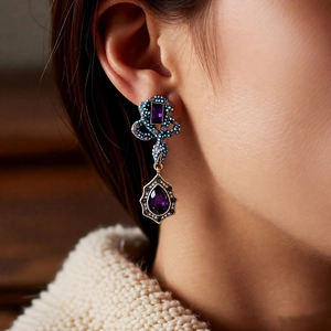 Close-up of vintage palace style drop earrings with purple gemstones and ornate metalwork