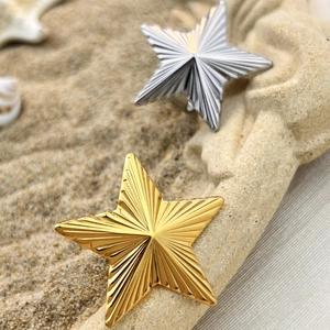Vintage gold and silver star rings with radial texture on a beach stone backdrop