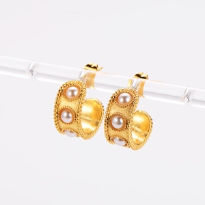 Macro view of vintage 18k gold C-shaped earrings with pearls on acrylic stand