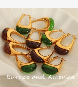 Close-up of vintage teardrop earrings with gold plating and colorful resin in a shell tray