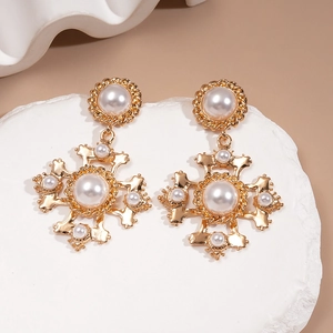 Vintage gold cross earrings with pearls in Baroque style on stone background