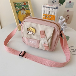 Close-up of pink and beige canvas crossbody bag with cartoon girl badge and LUNSME tag