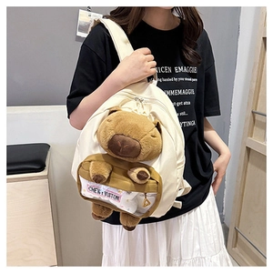 Detail of cute beige canvas backpack featuring a plush capybara and transparent PVC pocket