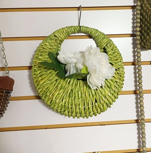 Close-up of green woven wall basket with white peony flowers for wall decoration