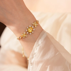 Detail eines Vintage Goldarmbands mit gelbem Edelstein und Zirkonblüten am Handgelenk
