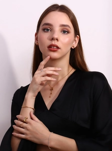 Detailed view of model wearing a gold bow earring, butterfly necklace and stacked rings