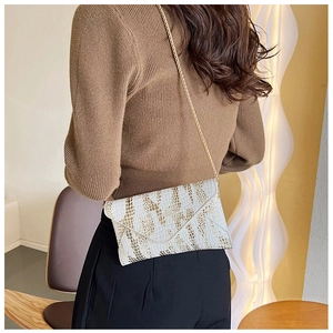 Detailed close-up of white embossed crocodile pattern bag with golden chain strap