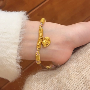 Detailed close-up of a red woven bracelet featuring a golden horse charm on a wrist