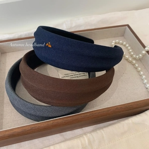 Three autumn fabric textured headbands in navy, brown, and grey on a wooden tray
