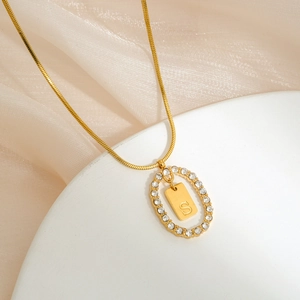 Close-up of gold-plated necklace with oval zircon frame and S letter pendant
