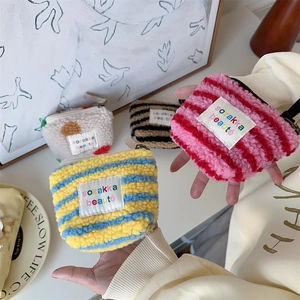 Close-up of plush striped sherpa cosmetic bags with metal zippers and woven labels