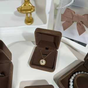 Detail of a gold moon pendant necklace with white mother-of-pearl in a brown velvet box