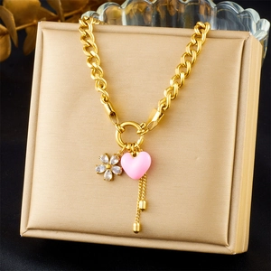Détail du collier plaqué or 18K avec cœur rose, breloque fleurie et pompons