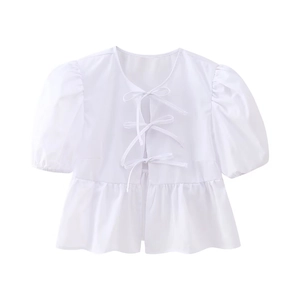 Detail view of a white puff sleeve blouse with adjustable front tie and ruffled hem finish