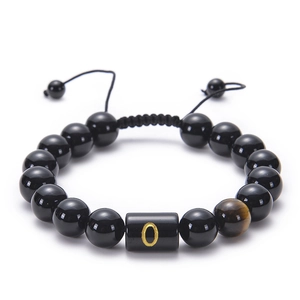 Macro detail of black agate beaded bracelet featuring a gold letter O and tiger eye stone