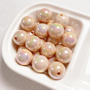Macro shot of 14mm iridescent champagne gold acrylic beads in a ceramic bowl